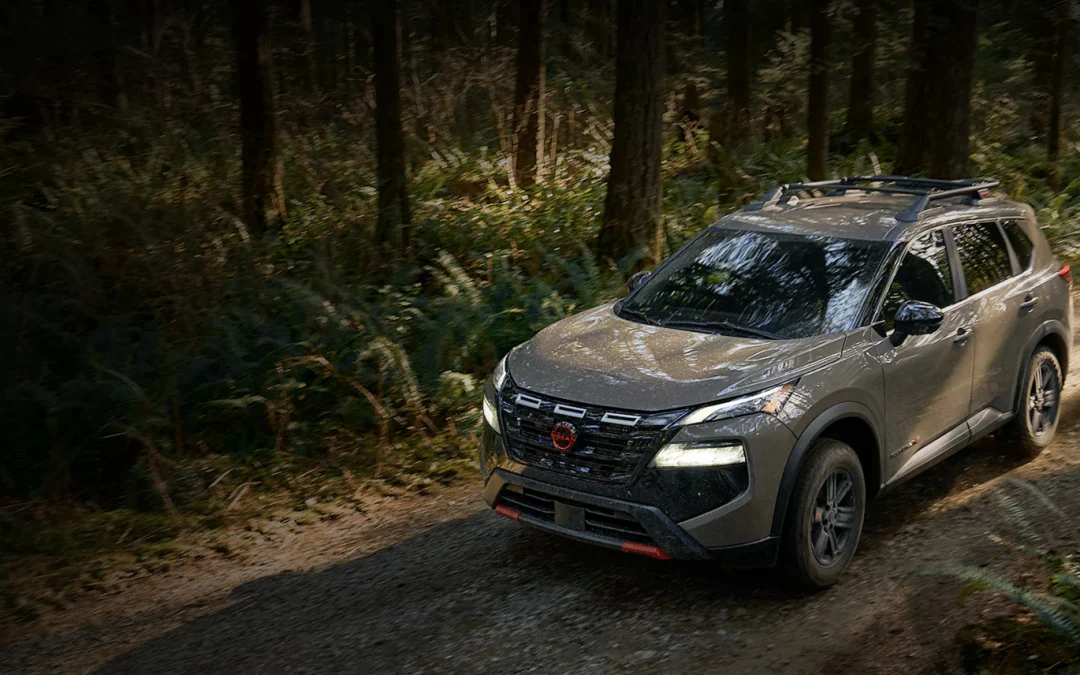 Nissan Rogue SUV driving on a wooded trail with roof rails and rugged exterior styling